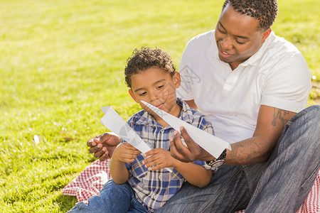 父亲和混血儿在公园里玩纸飞机图片