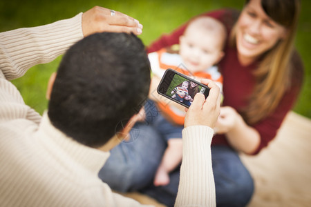 快乐的混合种族父母和婴儿男孩在公园外面自画像图片