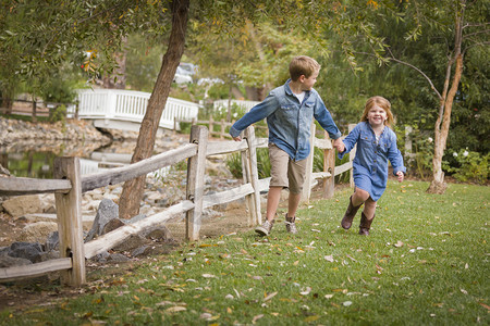 快乐的哥哥妹妹牵着手在草坪上奔跑图片