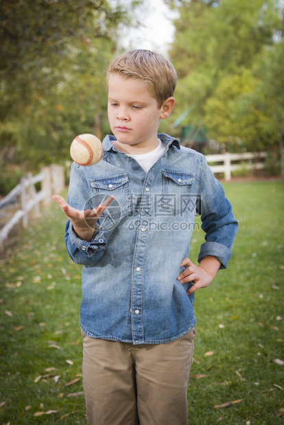 英俊的小男孩在公园里扔棒球图片