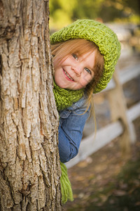 带着绿色围巾和帽子的可爱笑年轻女孩假扮在外面画肖像图片