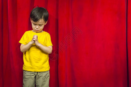 混血儿在红幕前祈祷背景图片