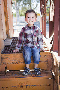 可爱的混杂种族男孩在外面玩得开心坐在铁路车台阶上图片