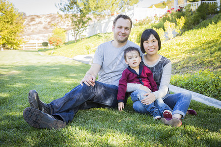 快乐的混合种族家庭在草地上玩得开心图片
