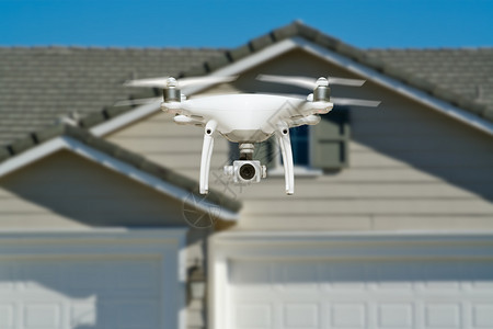 无人驾驶飞机在靠近房屋的空中飞行图片