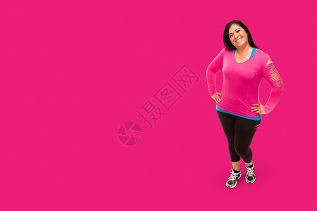 身穿运动服的中年西班牙妇女面对明亮的粉红背景图片