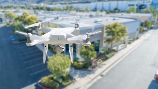 无人机在公司工业大楼附近的空中飞行背景图片