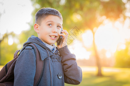 年轻的西班牙男孩在户外行走背着包在手机上说话图片