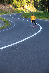 夏天的公路旅行美丽的风景和山路色女孩骑着滑板在横贯阿尔卑斯山罗马尼亚图片