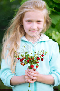 快乐的小女孩抱着一棵野草莓图片
