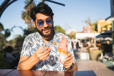 年轻人在户外吃冰淇淋时享受阳光的天气图片