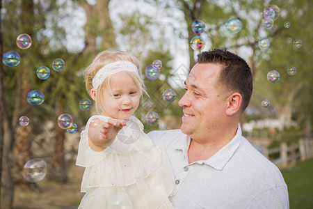 父亲抱着女儿在公园玩泡泡图片