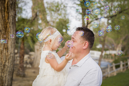 父亲抱着女儿在公园玩泡泡图片