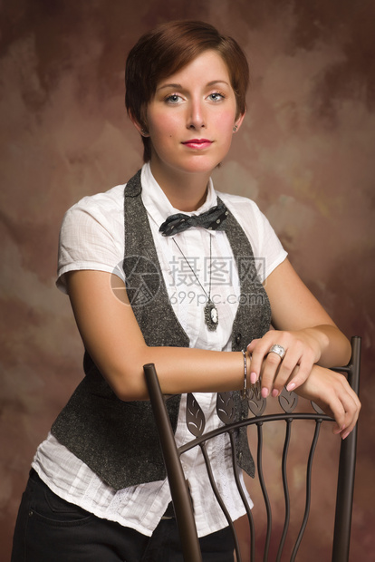 红发年轻成女肖像仰靠椅子与肌肉背景