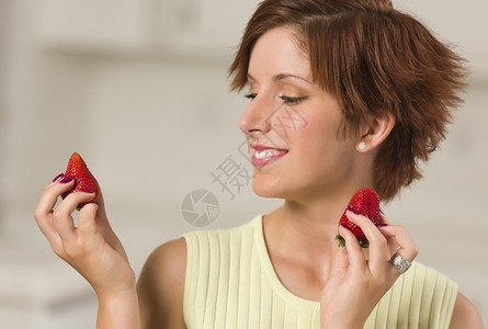 漂亮的红发女人在厨房里拿着草莓图片