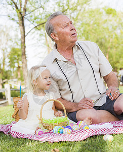 祖孙两人在野餐垫子上向远方望去背景图片