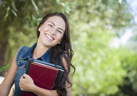 在户外有课本的年轻女学生图片