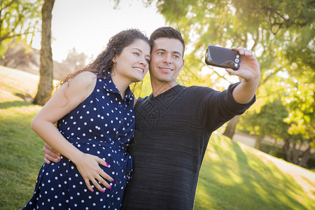 怀孕妻子和丈夫在公园户外拍摄自己手机照片图片