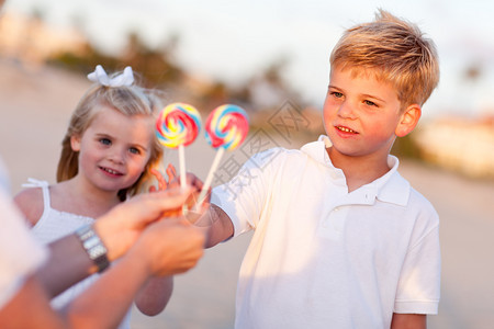 可爱的哥和妹挑选棒糖出他们的妈在海滩上图片