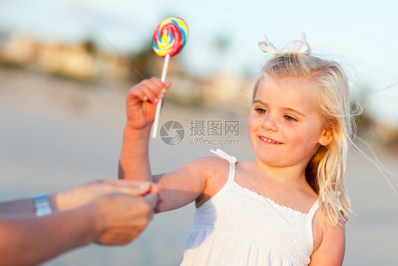 可爱的小女孩从海边妈那里挑棒糖图片