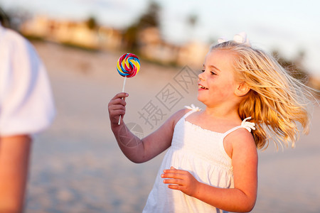 可爱的小女孩享受她的棒糖在海滩外面图片