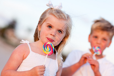 可爱的小女孩和弟享受他们的棒糖在海滩上图片