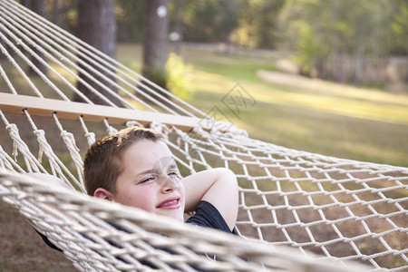 笑的年轻男孩在外面吊床上享受一天的快乐图片