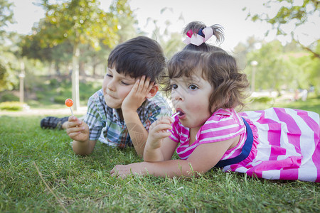 兄妹在草地上吃棒棒糖图片