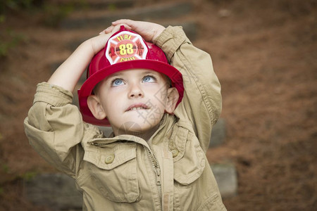 可爱的男孩消防员帽子在外面玩图片