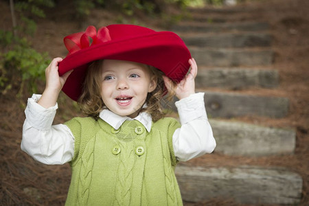 快乐可爱的女孩戴着红帽子在外面玩背景图片