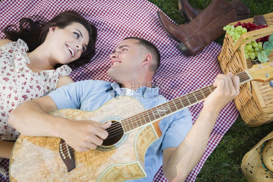 男子躺在草坪弹吉他给女友听图片
