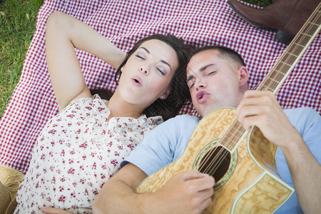 男子躺在草坪弹吉他唱歌给女友听图片