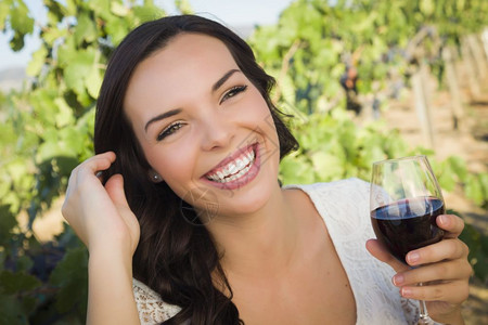年轻成女子在葡萄园里喝杯酒图片