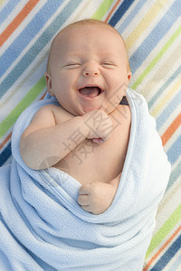 男婴儿躺在毯子里开心的笑起来图片