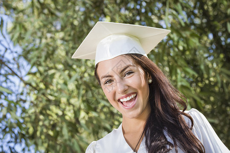 大学生穿着白色礼服手持文凭幸福的高清图片素材