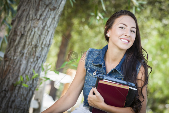 在户外有课本的年轻女学生图片