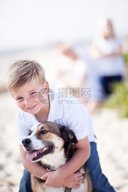 英俊的小男孩在海滩上玩狗图片