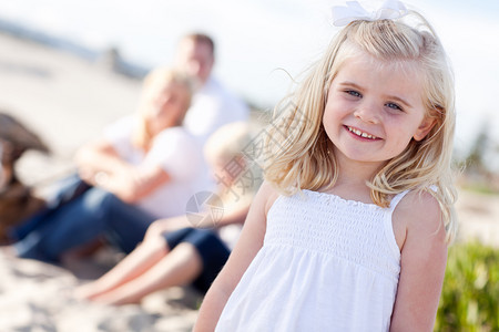 可爱的金发小姑娘和家人在海滩玩得开心图片