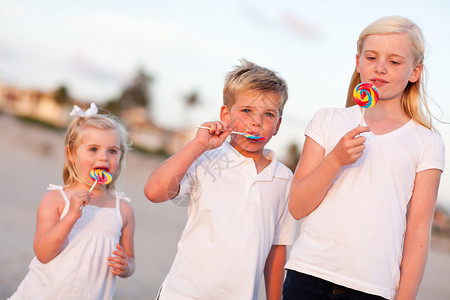 可爱的兄弟和姐妹们享受他的棒糖在海滩上图片