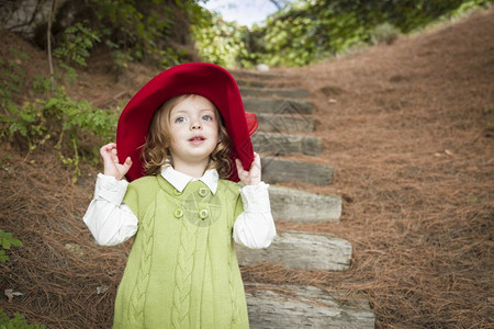 快乐可爱的女孩戴着红帽子在外面玩图片