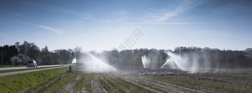 春天在青蓝空下农用区Holand喷洒给地球浇水图片