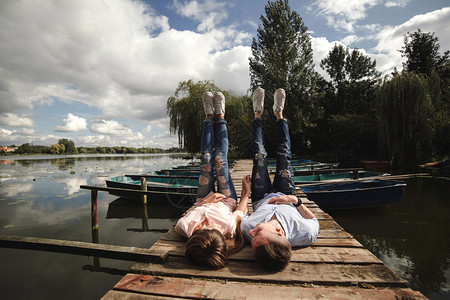 年轻夫妇躺在湖边的木桥上图片