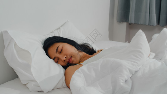 年轻的青女孩感到愉快的休息躺在床上早家的卧室里感到舒适和平静图片