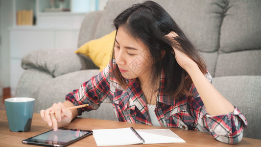 女学生在家里做功课女学生喝咖啡用平板电脑在家里的客厅搜索沙发图片