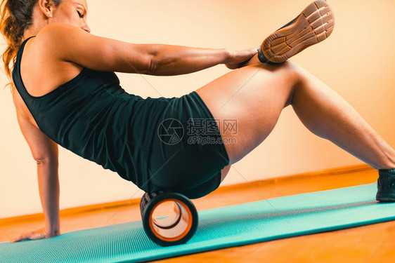 使用泡沫滚来进行肌肉和fasci按摩的妇女泡沫滚fasci和肌肉按摩机图片