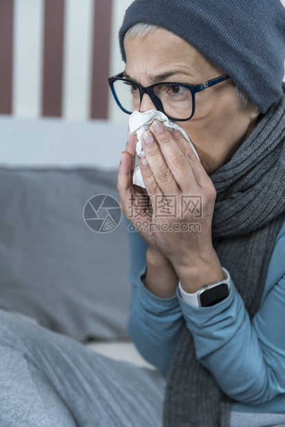 发烧的老年女人吹鼻涕坐在床上图片