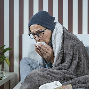 发烧的老年女人吹鼻涕坐在床上图片