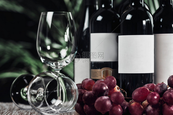 装有空葡萄酒杯不同瓶红葡萄酒和新鲜合起来图片