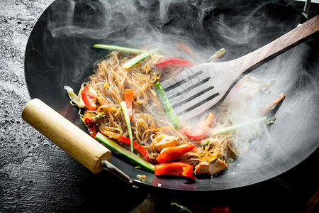 黑色生锈背景的锅里有热大豆面条图片