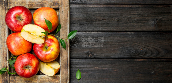 红苹果有叶子和切片放在木箱中黑暗的木头背景上红苹果在木箱中图片